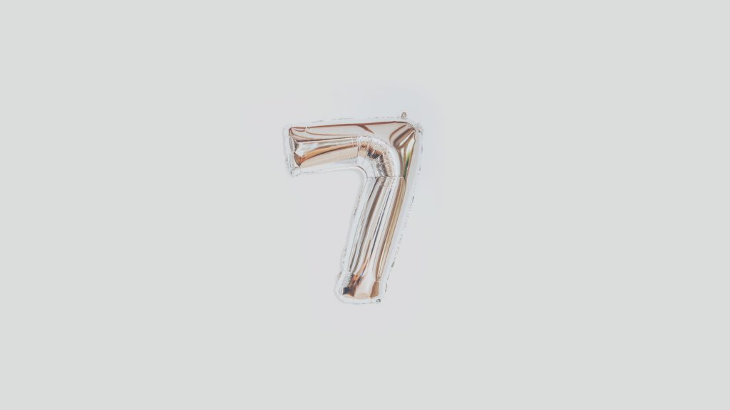 A metallic, silver-colored helium balloon shaped like the number 7 against a plain white background.